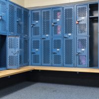 Blue metal cage lockers in a locker room with some doors open an